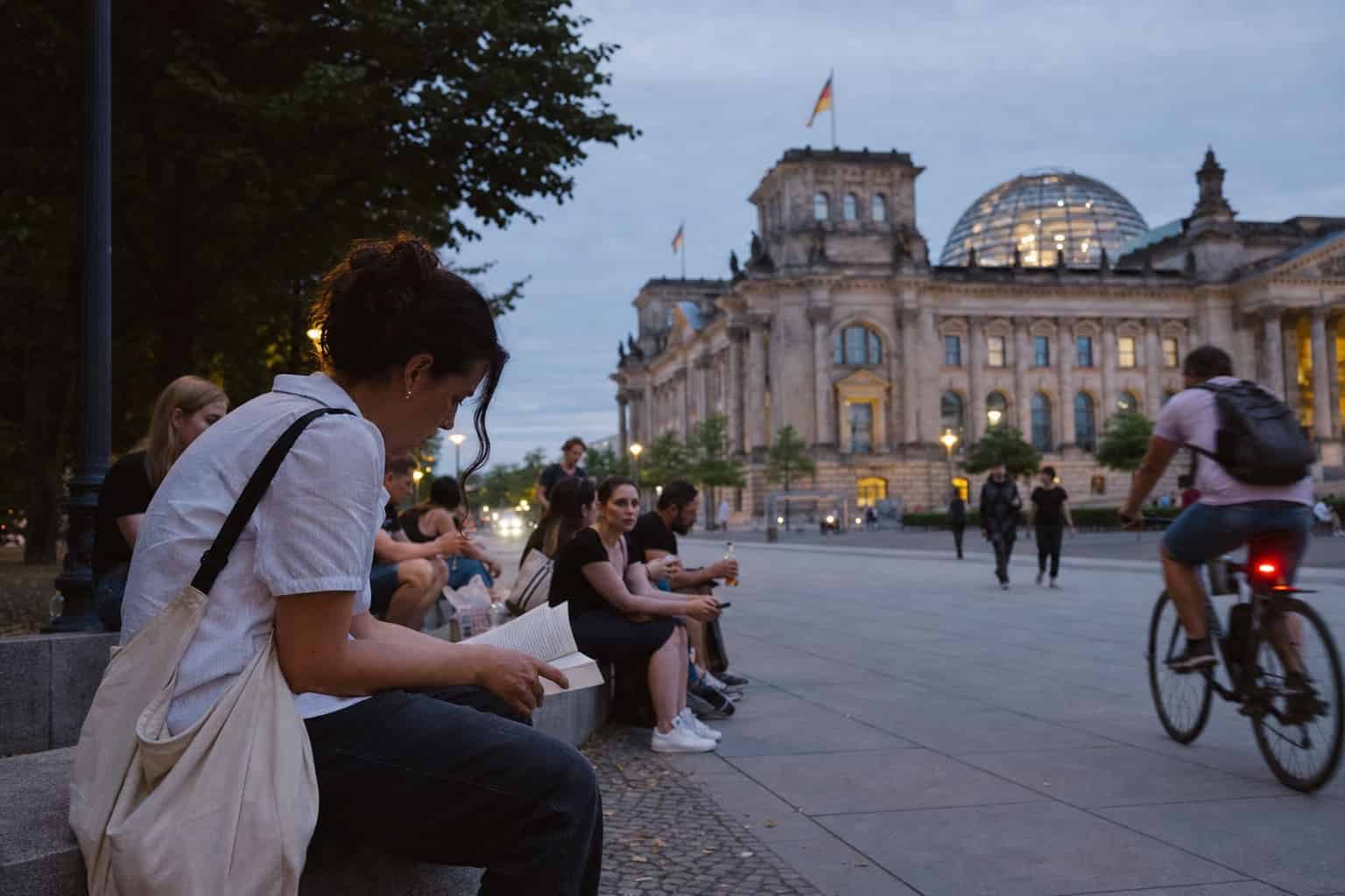 Frau liest auf einer Bank vor dem Reichstagsgebäude in Berlin